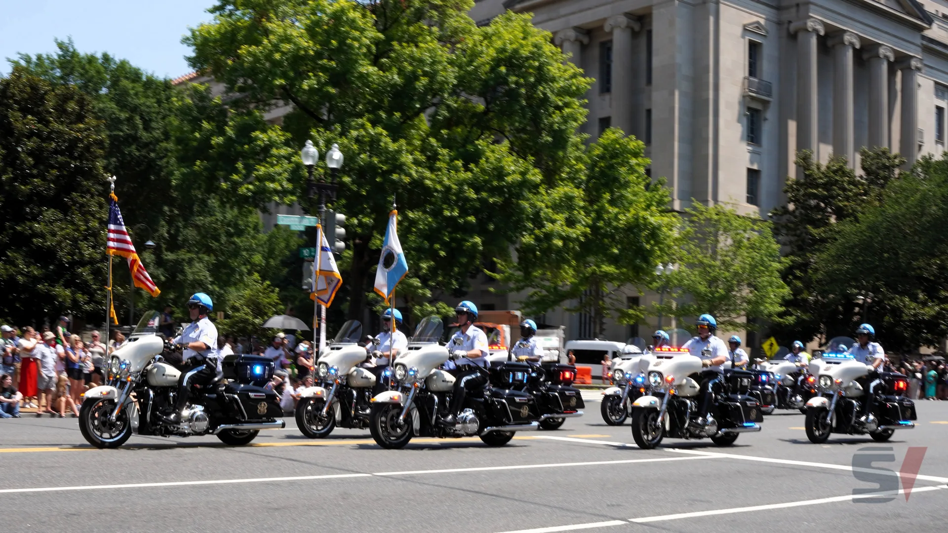 Motorcycle police officers in uniform lead the parade with flags.