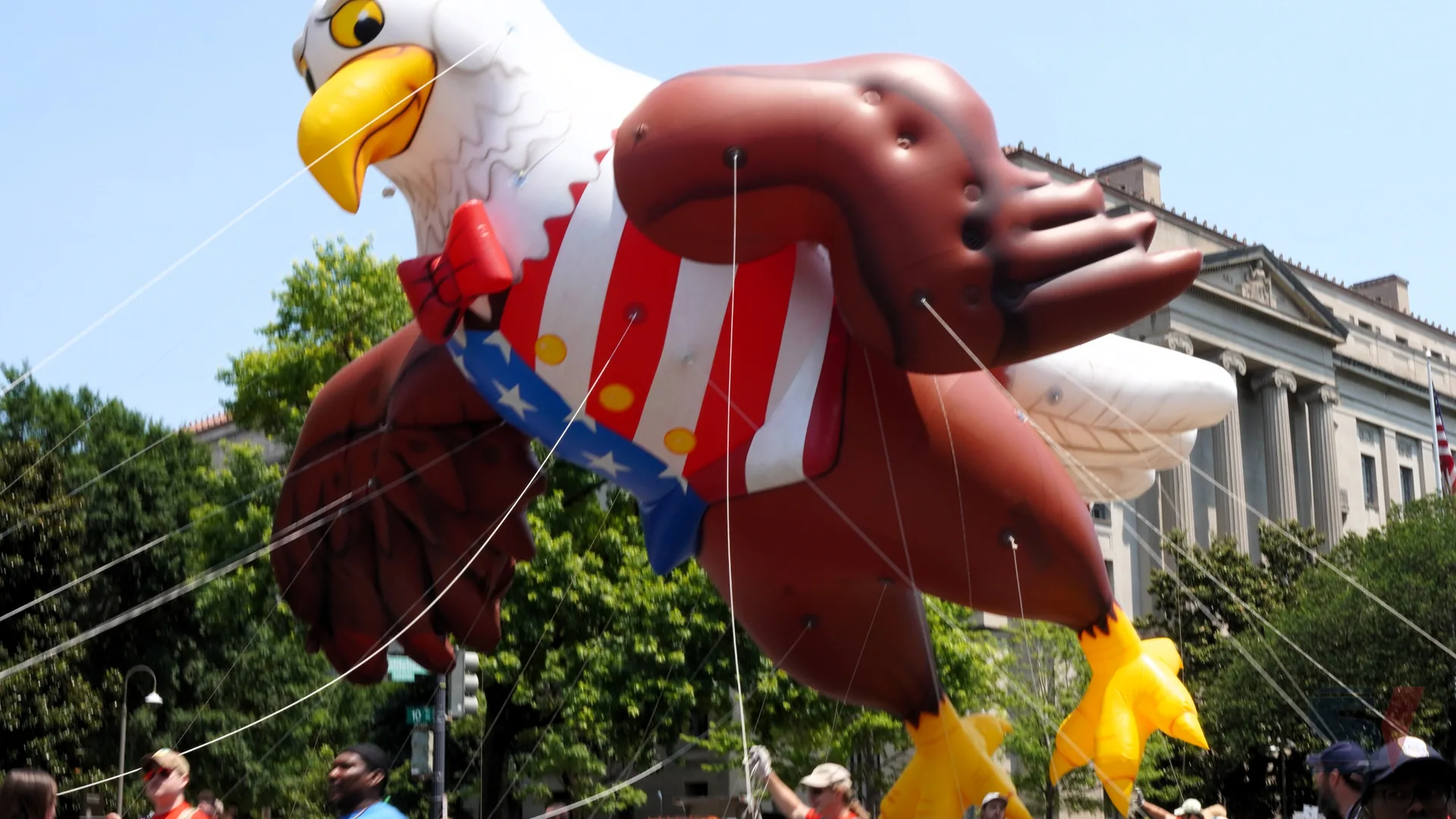 Large eagle balloon character with patriotic colors in a parade.