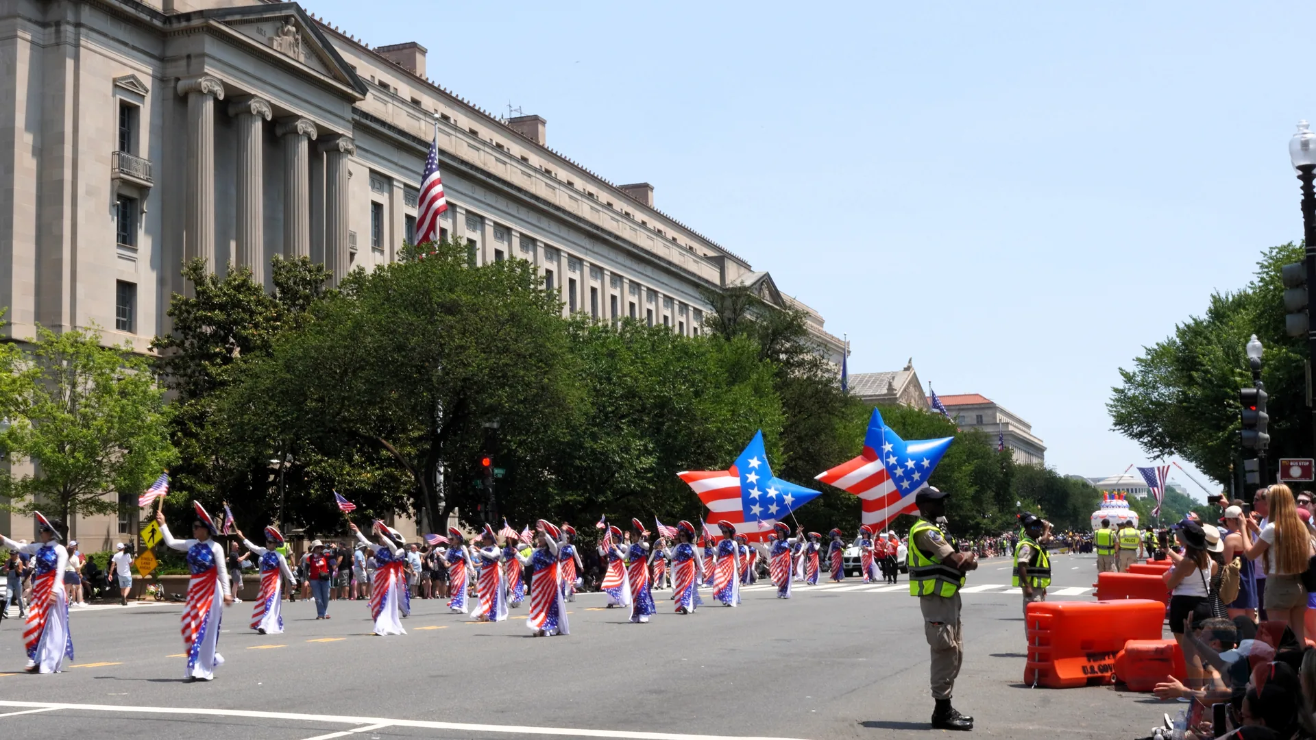 Participants in patriotic costumes wave flags during July 4th parade.