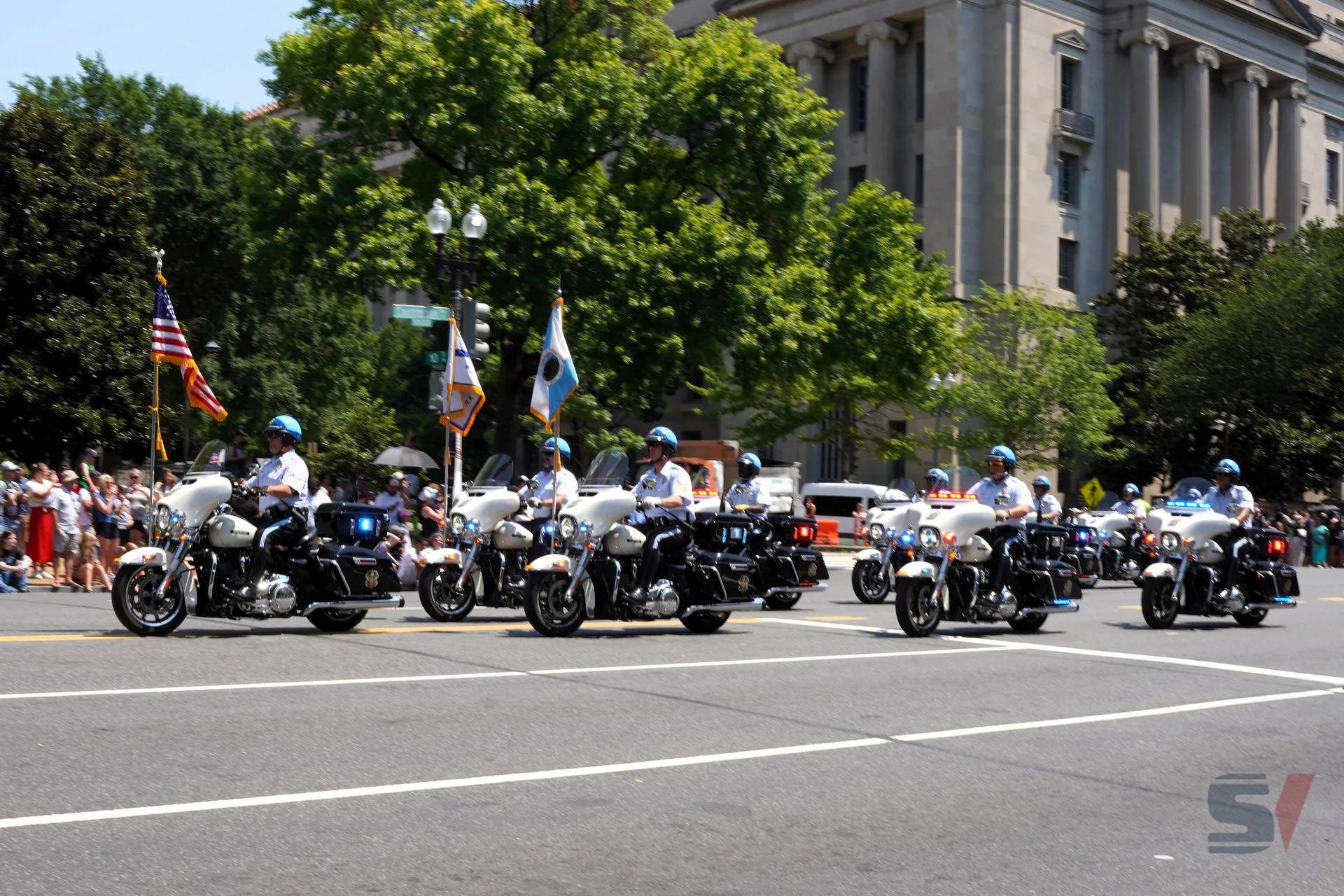 Motorcycle police officers in uniform lead the parade with flags.