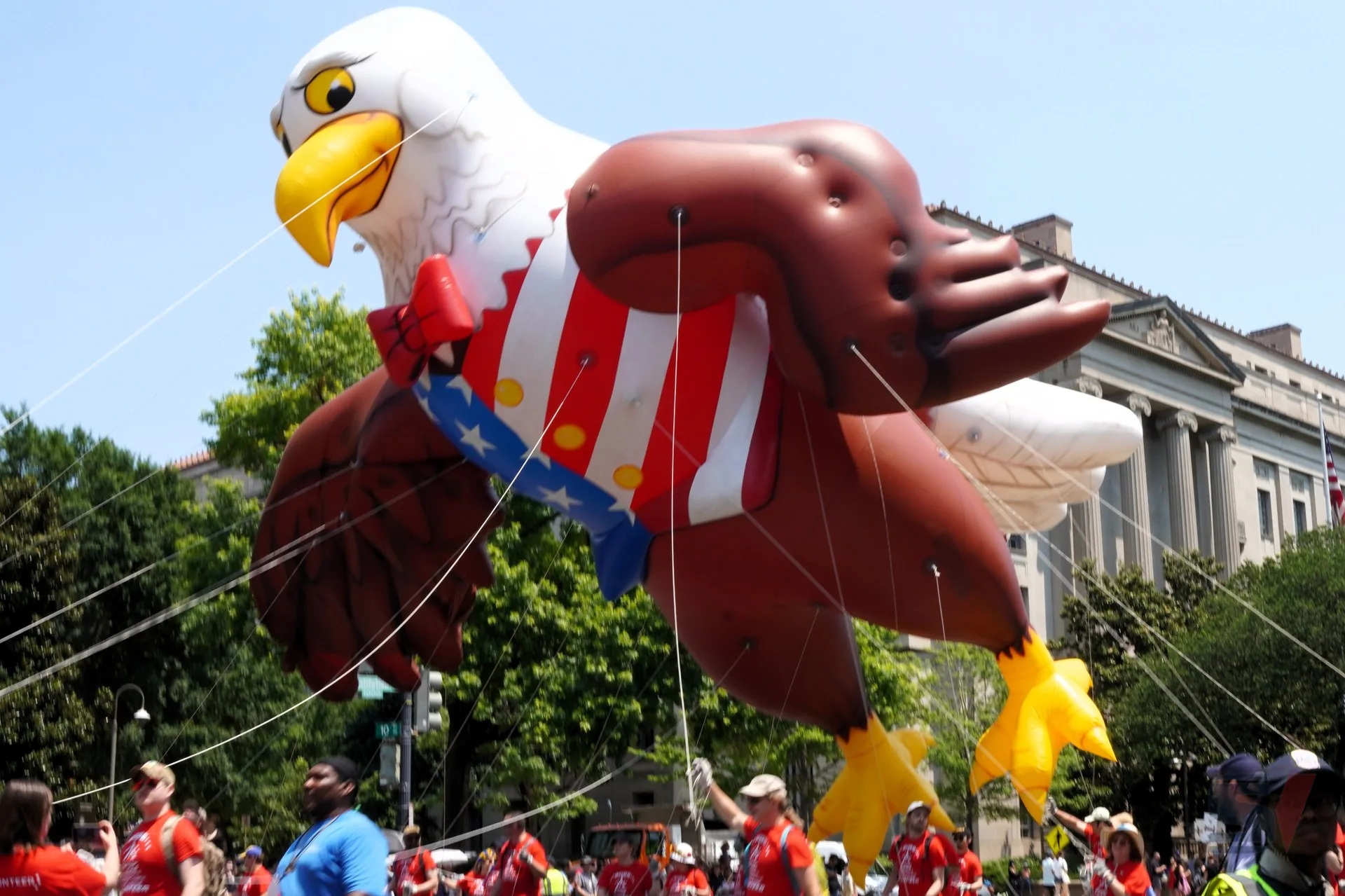 Large eagle balloon character with patriotic colors in a parade.
