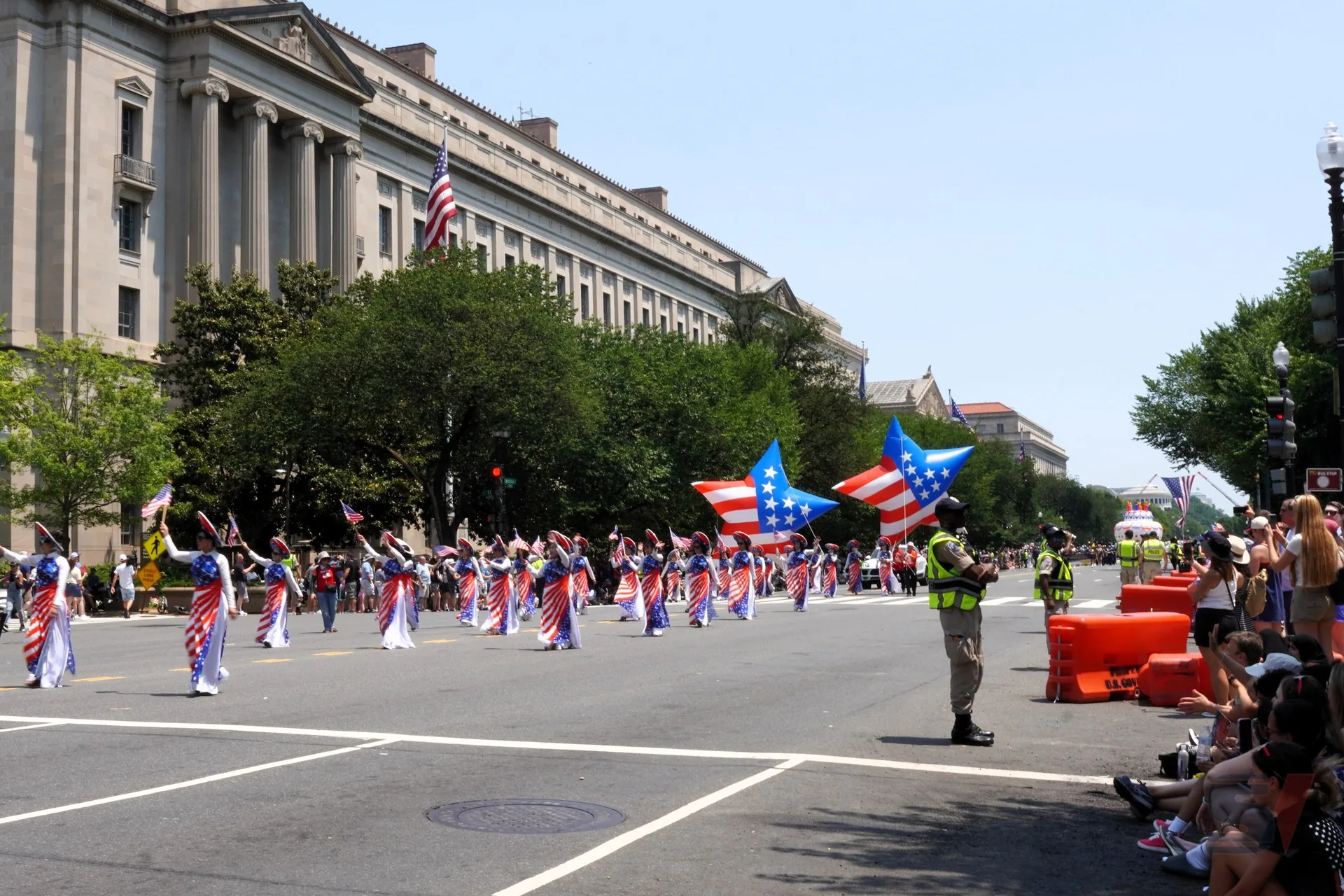Participants in patriotic costumes wave flags during July 4th parade.