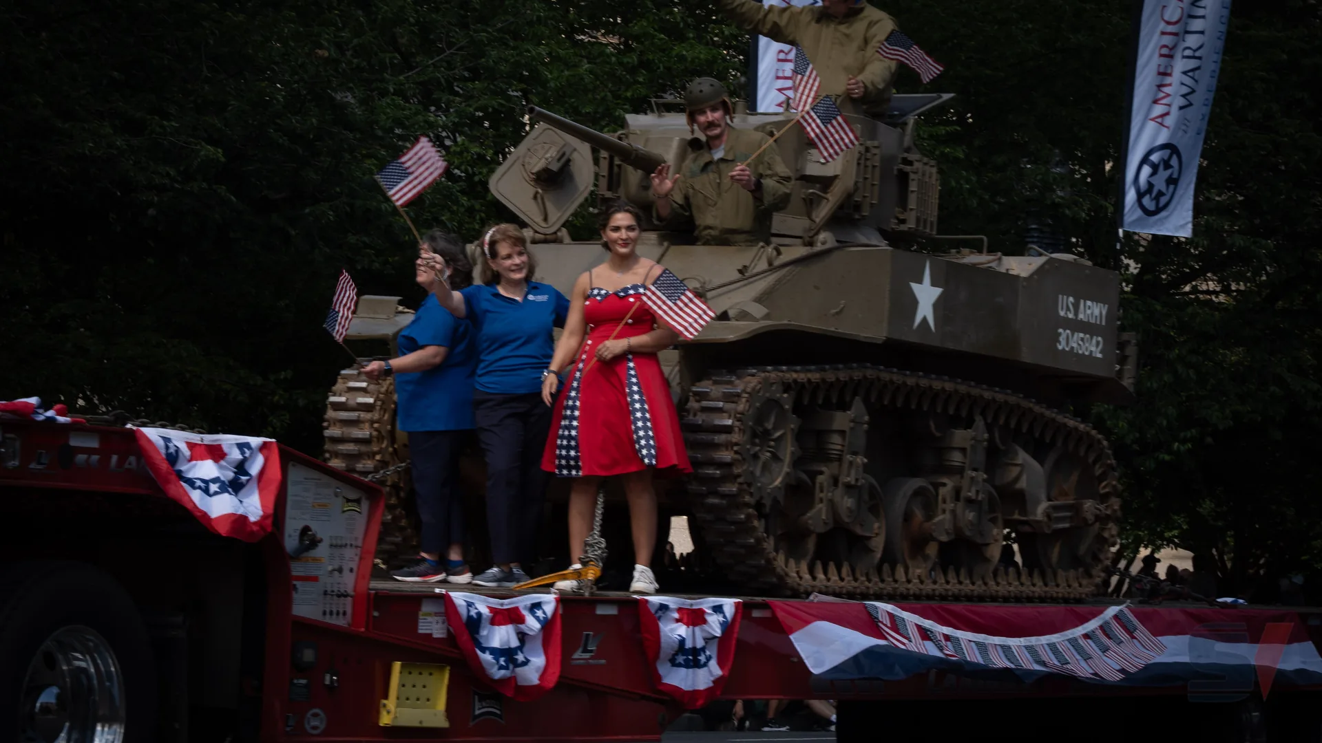 Participants waving flags on a tank during the National Memorial Day Parade.