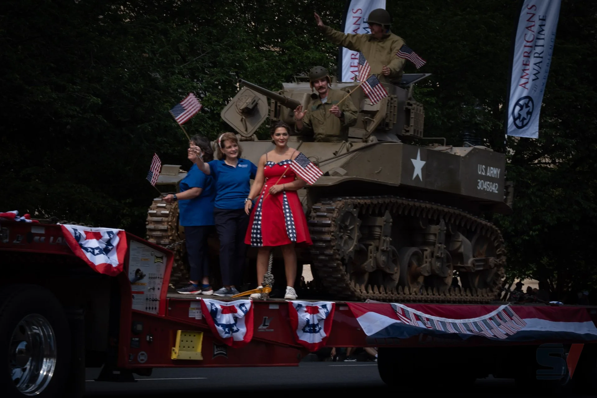 Participants waving flags on a tank during the National Memorial Day Parade.
