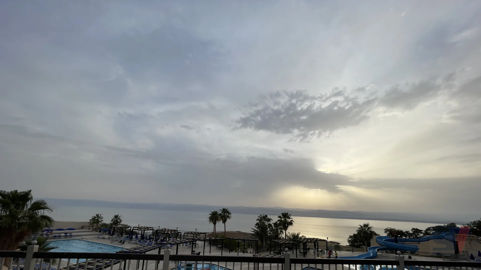 A serene view of pools and the Dead Sea at sunset.