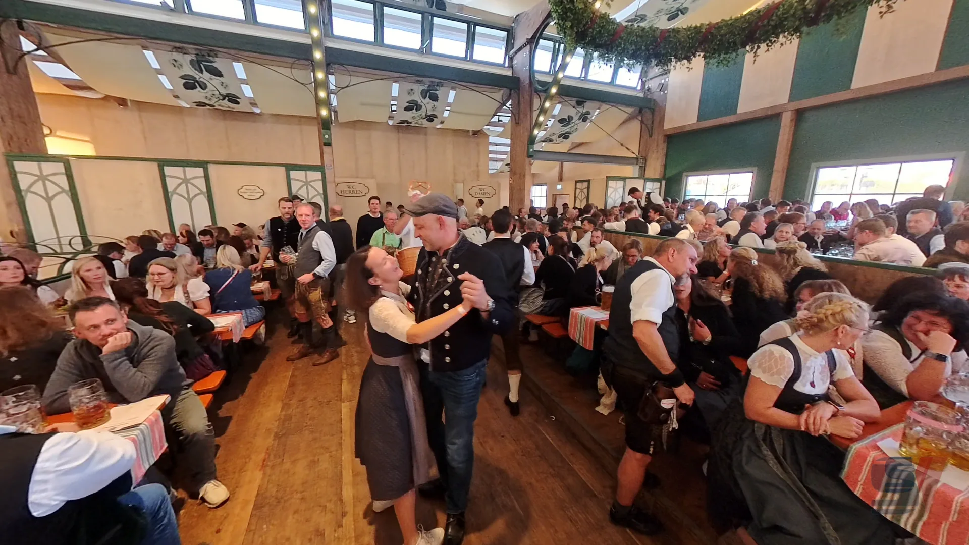 A couple dances together in the crowded Bräurosl tent at Oktoberfest.