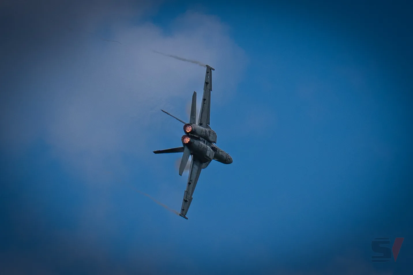F/A-18 Hornet executing a high-speed turn with afterburners lit.
