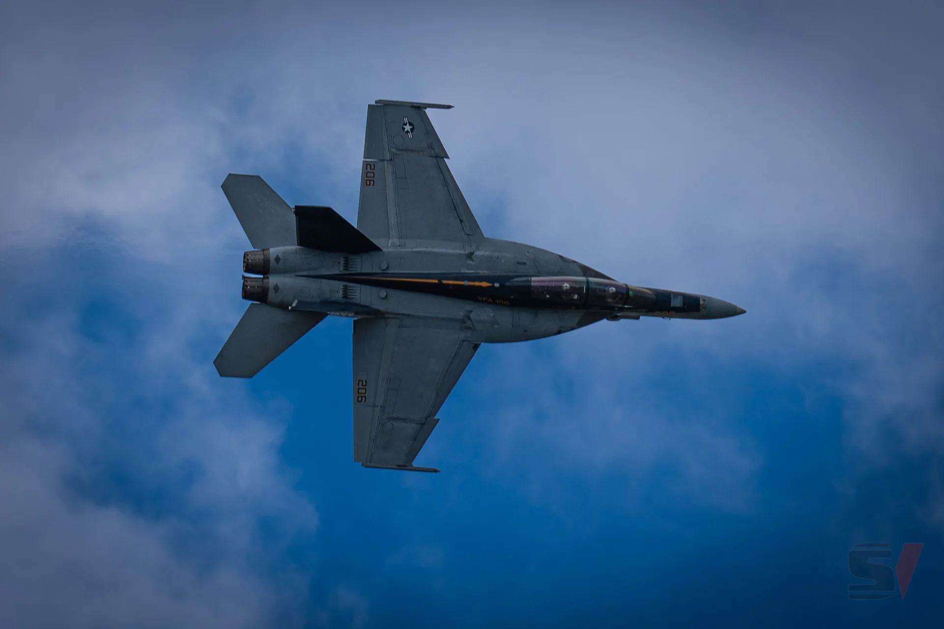F/A-18 Super Hornet flying in a blue sky with clouds.
