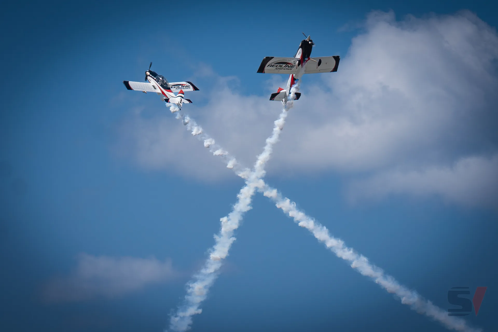 Two aircraft performing acrobatic maneuvers with smoke trails.