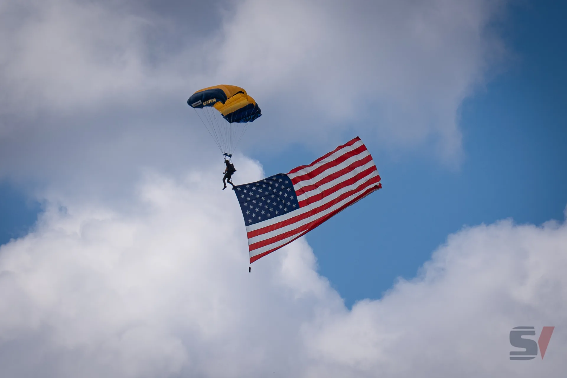 A parachutist descending with an American flag during the air show.